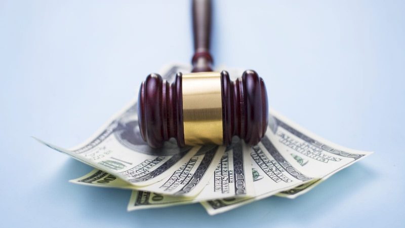 A judge's gavel resting on a pile of hundred-dollar bills.